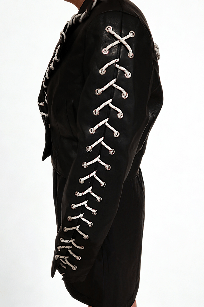 Model wearing The Edge-Laced Jacket by Chez Neeba — cropped black leather jacket with white lace-up detailing, limited edition Dubai fashion.